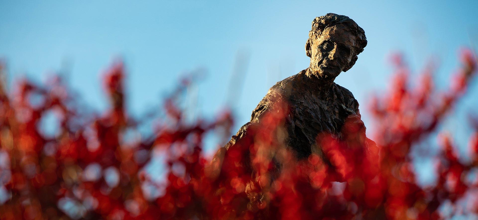 路易斯·365betapp的雕像，前景是红色的花朵
